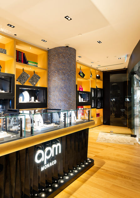 APM Monaco's luxury retail interior with warm timber flooring, black detailing and illuminated display shelving by Hellospace