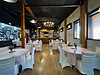 Restaurant event space with round tables, white chair covers, a chandelier and a painted mural