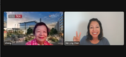 Zoom interview screenshot. Lilly is on the left wearing a pink blouse with white design and her background is a busy city scene at dusk. Mai Ling is on the right wearing a dark gray shirt and is and holding up the piece sign on her right hand. 