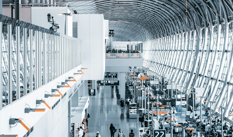 Spacious modern airport terminal with curved steel ceiling, gate signs 19–22, and travelers walking through.