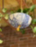 Hanging plant pot with a blue bubble glaze and green plants spilling out of it.