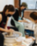 Group pottery workshop students learning how to center their clay on the wheel.