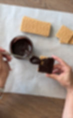 Covering a graham cracker in melted chocolate.