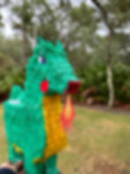 A green dragon pinata hanging from a tree.