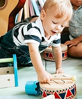 Little kid playing with a wooden drum set.webp