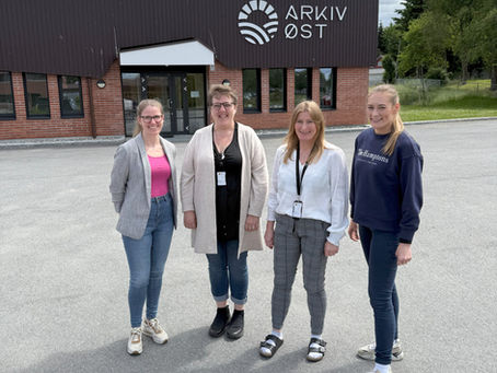 Bildet viser fire damer oppstilt ved siden av hverandre. I bakgrunnen ligger et bygg med logo til Arkiv Øst på veggen.