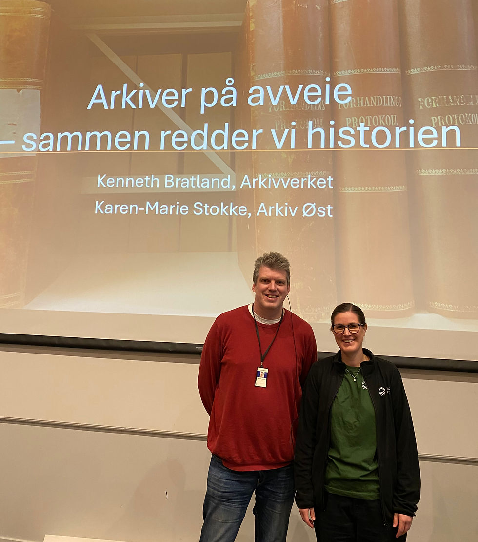 En mann og en kvinne står oppstilt foran et lerret. Teksten på lerretet bak dem er som følger: Arkiver på avveie - sammen redder vi historien.