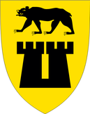Sarpsborg kommunevåpen. Svart bjørn plasser over en svart borg på gul bakgrunn. 