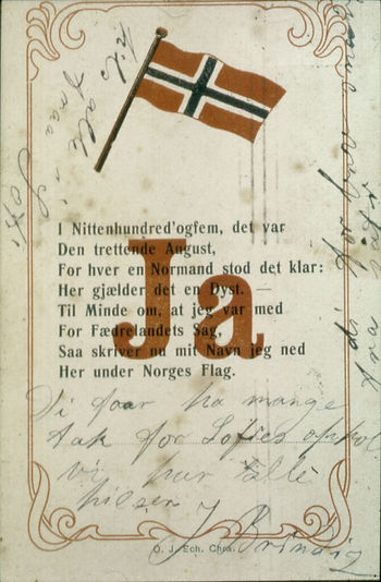 Nærbilde av et dokument med et norsk flagg og med rød skrift skrevet er stort "ja". Rundt på arket er det håndskrift. Midt på arket står med trykte bokstaver: "I Nittenhundred`og dem, det var Den trettende August, For hver en Normand stod det klar: Her gjelder det en Dyst. Til Mindre om, at jeg var med For Fædrelandets Sag, Saa skriver nu mit Navn jeg ned Her under Norges Flag.