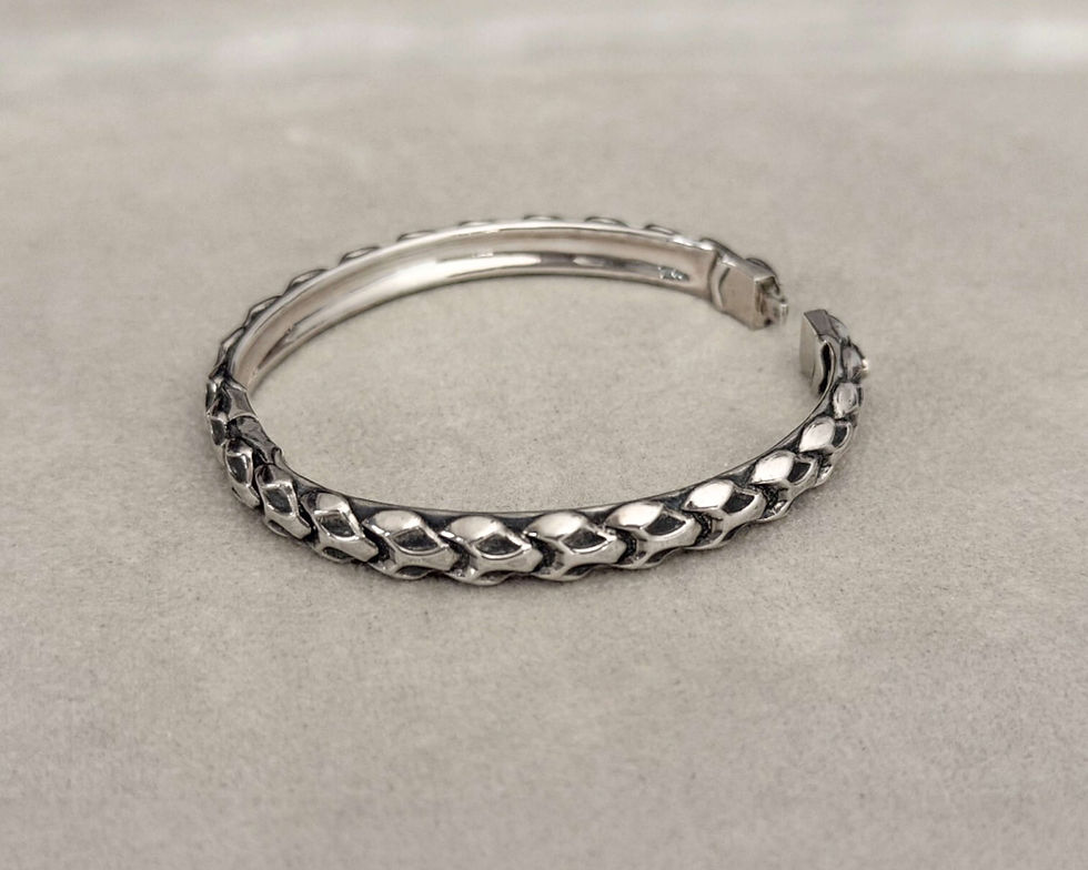 Thumbnail: Sterling silver Ophidian bangle bracelet on a light gray surface, photographed in natural light