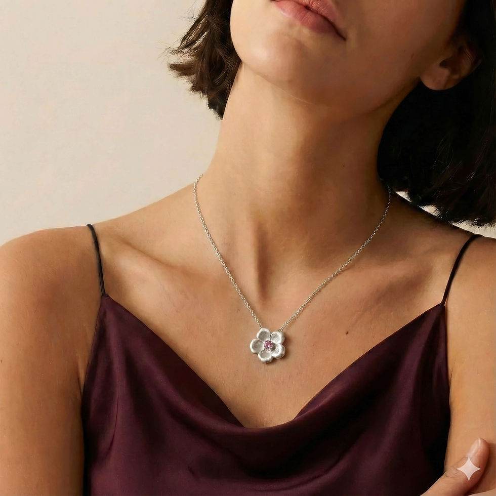 Model wearing the Primrose pendant necklace with a silver flower pendant and a pink center stone on a delicate chain (close-u