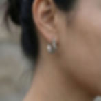 Close-up of ear wearing Ophidian huggie earrings in sterling silver