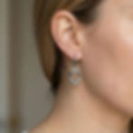 Close-up of a model wearing Venus Bare Open Face drop earrings with black spinel