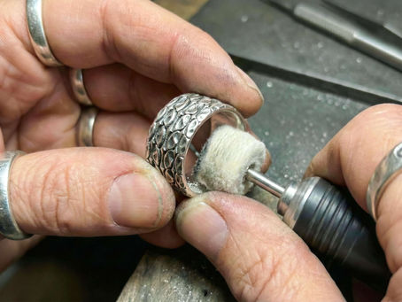 Artisan crafting a handcrafted silver ring by hand, showing detailed metalwork and texture during the jewelry-making process.