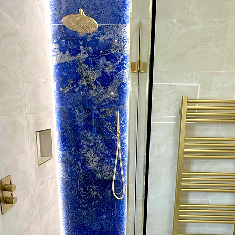 Blue and gold bathroom design with niche in walk in shower.