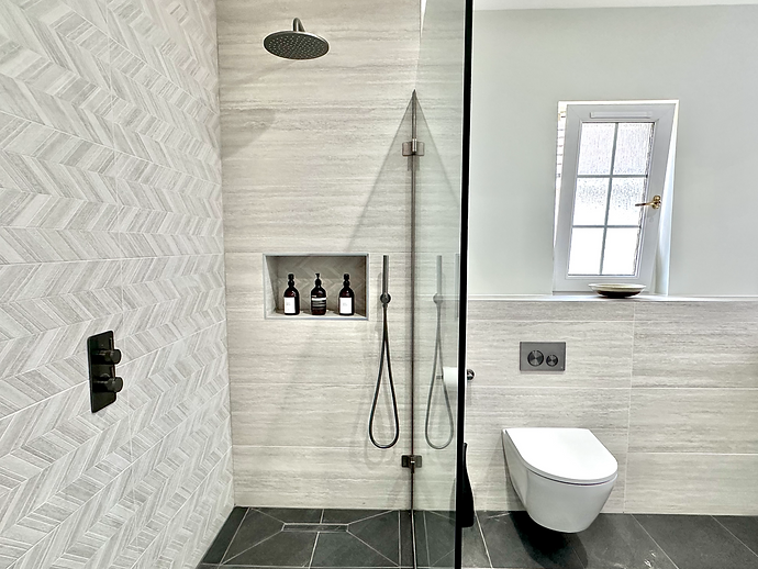 Grey bathroom tiles with niche in walk in shower