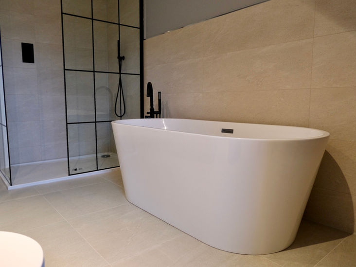 large freestanding white bathtub with black tap