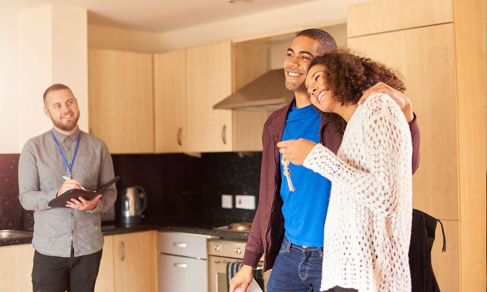 Photo of a happy couple holding a pair of keys, inside a kitchen with their letting agent looking at them and also smiling