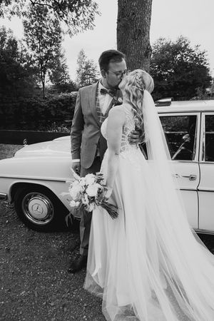 brautpaar küsst sich vor einem oldtimer fuchsloch gut voswinckel wipperfürth
