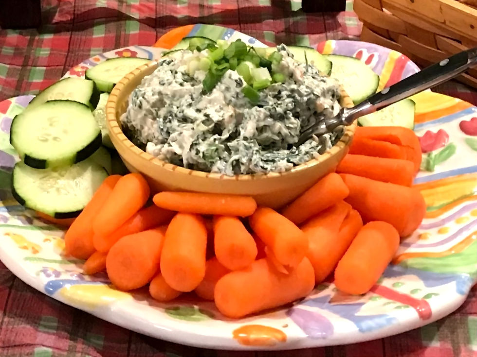 spinach dip surrounded by cucumbers and carrots