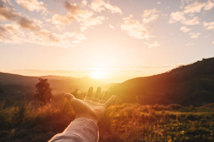 Young man hand reaching for the mountains during sunrise and beautiful landscape.jpg