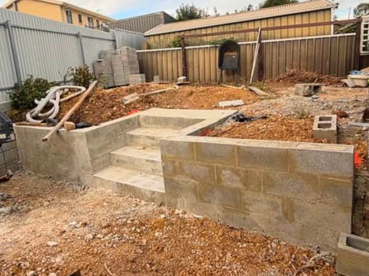 Stepped besser block retaining wall construction in progress by PrimeHouse.Pro Services Adelaide showing excavation, structural wall installation and outdoor landscaping works.