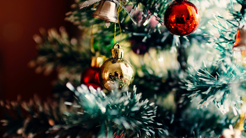 Close-up of a decorated Christmas tree with golden and red ornaments, silver bells, and green tinsel, creating a festive, cozy mood.
