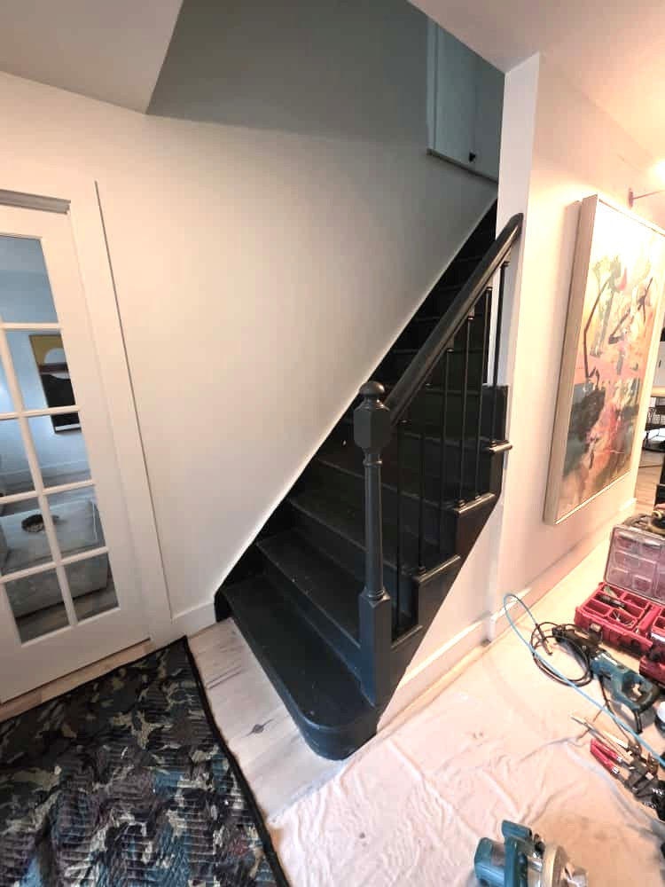 Basic black-painted wood and metal stair railing with simple square balusters.
