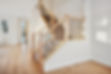 Staircase with a wooden railing and a carpeted landing. The staircase is in a large open s