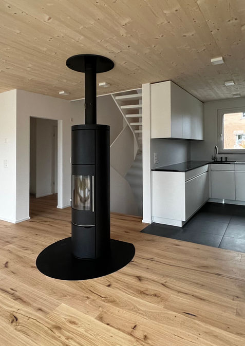 Innenraum mit Parkett und Holzdecke, freistehender Kaminofen, Kücheund Treppe