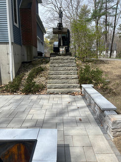 Stone steps with a retaining wall next to a patio. Hardscape and Landscape Designs.