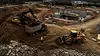 AI pedestrian detection solutions for heavy equipment — aerial view of construction site with excavator, dump truck, and workers on foot in active zones