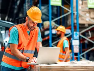 EHS manager using forklift pedestrian safety systems data on a laptop in a warehouse environment