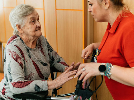 A compassionate caregiver talking with a senior woman using a walker in a Vancouver senior living facility.