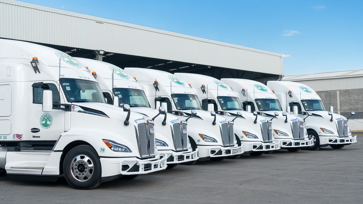 Fila de camiones de carga blancos estacionados en almacén.