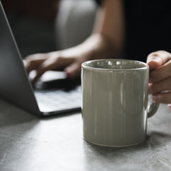 image of a woman working in a laptop holding a cup of coffee - project manager