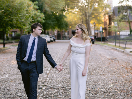 Emily and Jackson walking hand in hand on the brick streets during their Lockerbie Square engagement session at golden hour.