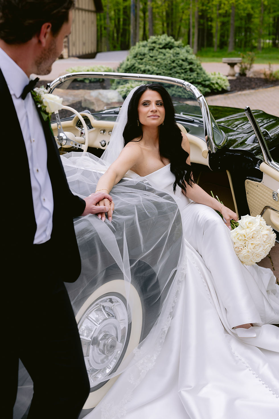 Bride and groom standing beside a black 1958 Corvette during wedding portraits in Indiana