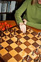 A person moving a chess piece on a wooden board, creating a calm, intentional scene that reflects the thoughtful approach of Palomo Therapy & Coaching.