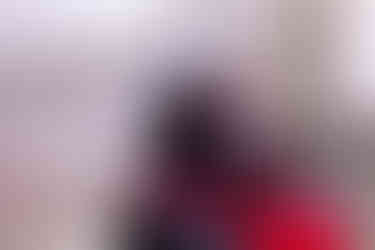 an alternative couple dressed i black and red gothic wedding attire kiss behind their gothic cake