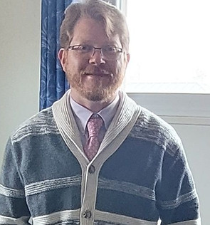 Man in patterned cardigan and glasses