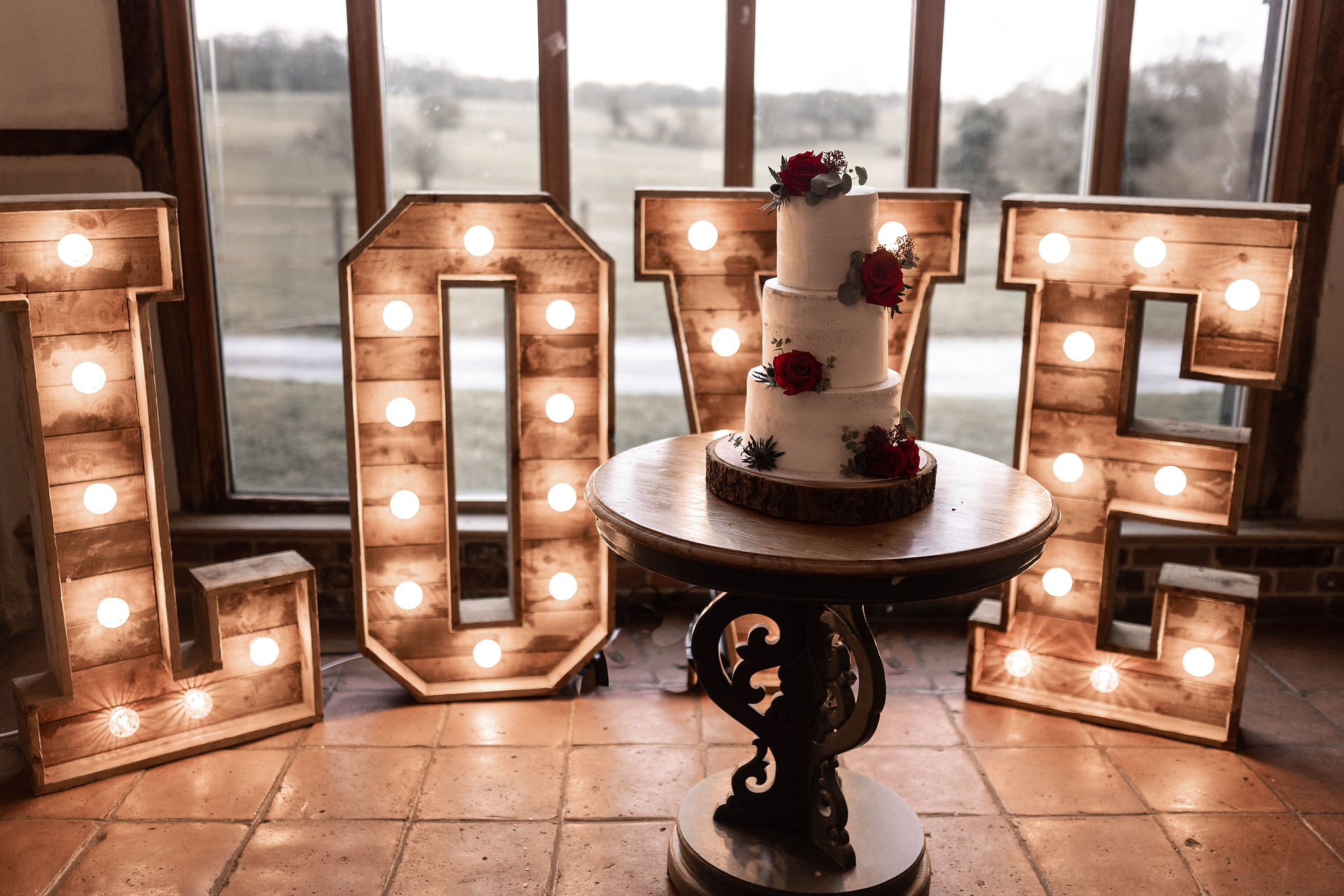 The wedding cake in front of light up love letters