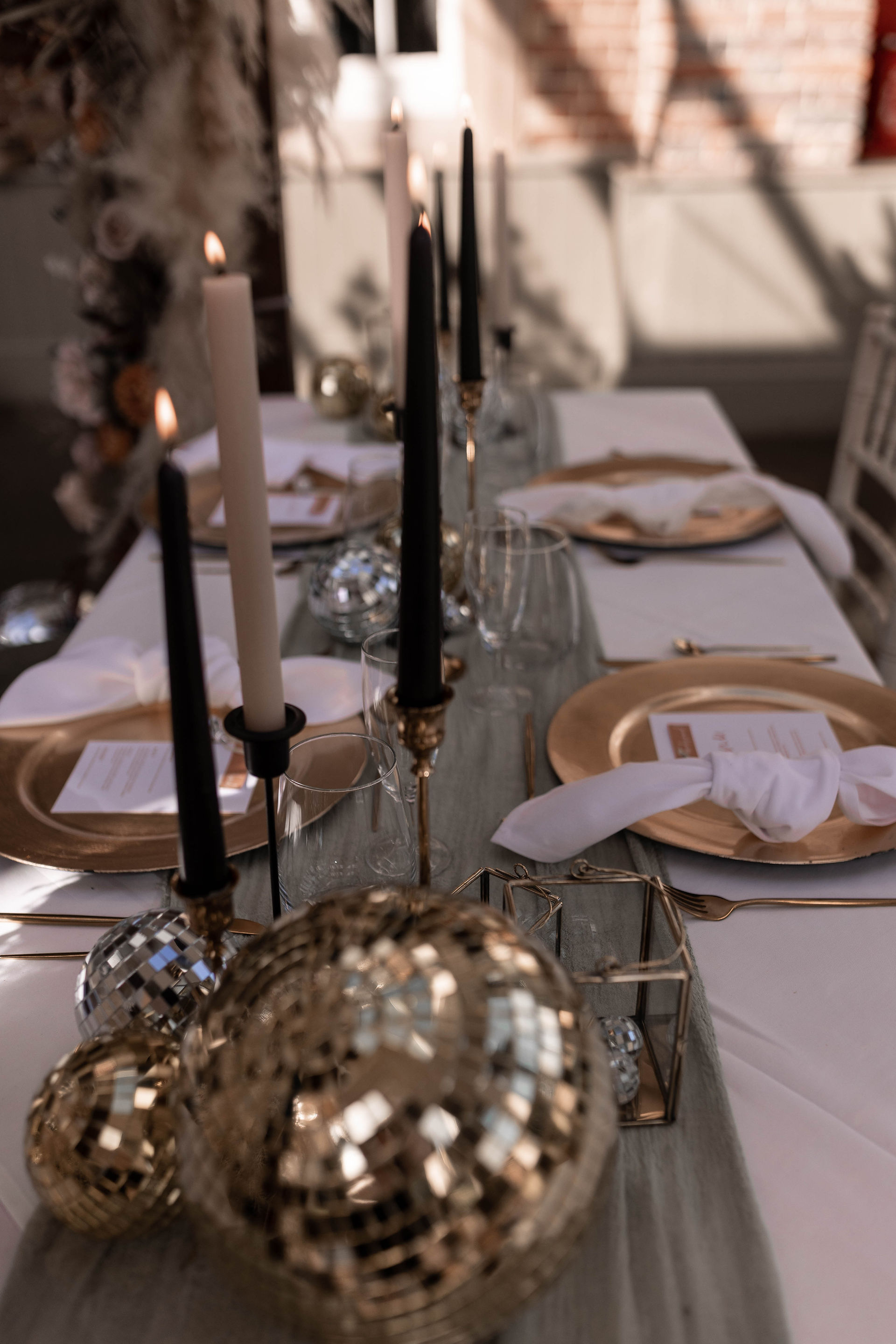 Black and white candles, silver and gold disc balls on sage green table runner