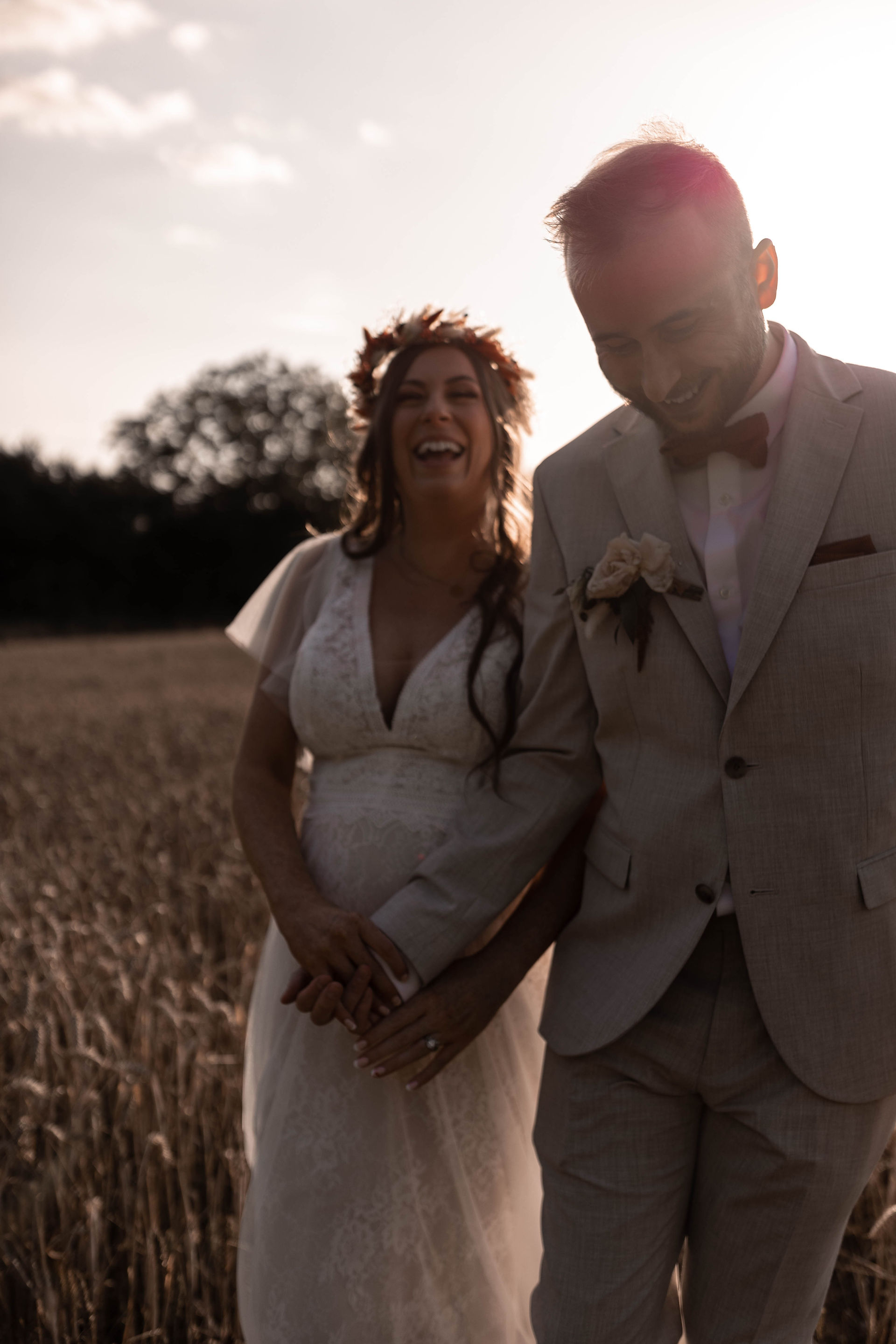 Bride and groom laughing in golden hour portraits in wheat field