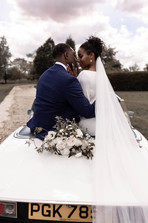 The bride and groom sitting on the back of a Triumph Stag