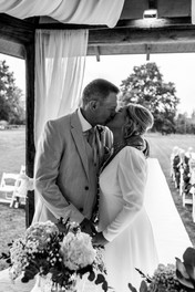 The bride and groom share their first kiss as husband and wife as their guests look on at the ceremony in the gazebo at That Amazing Place, Essex