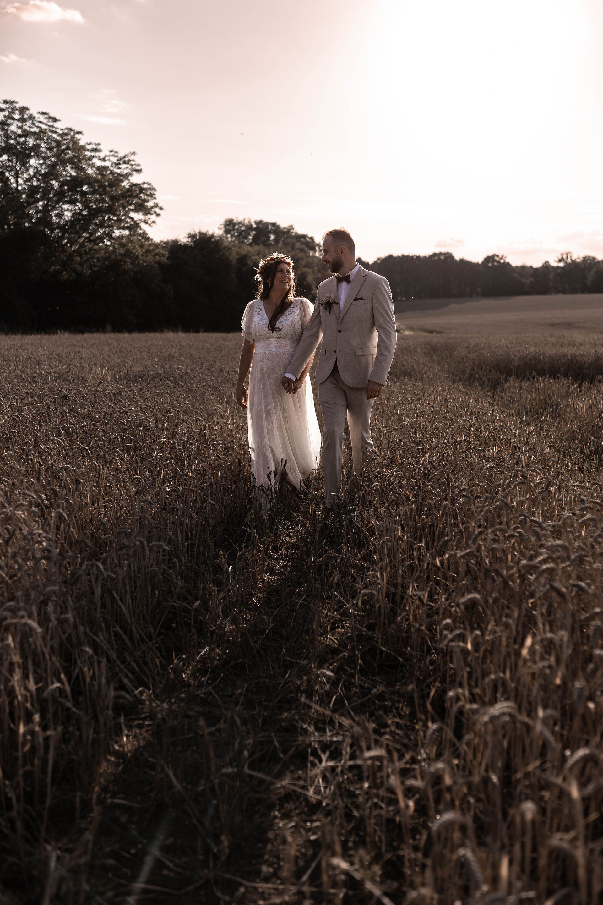 Bride and groom walking through Wheat field golden hour