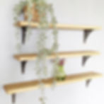 three wall mounted narrow wooden shelves of different lengths with decorative metal brackets w