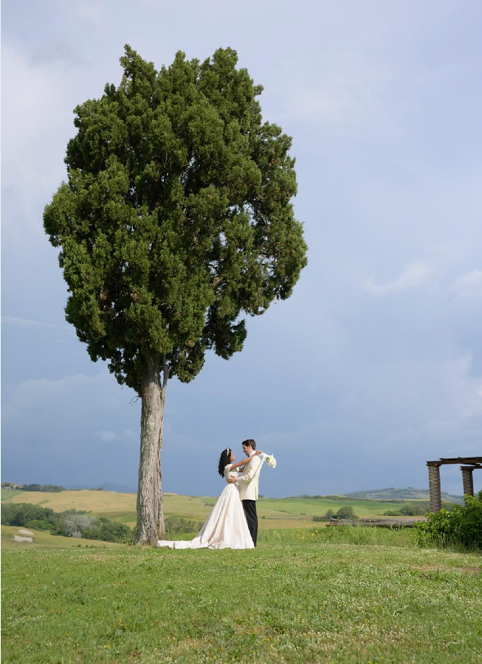 Elegant couple dancing near a tall tree on their wedding day, The Magic of Bespoke Wedding Dresses.