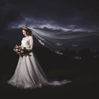 Bride wearing Suzanne Neville wedding dress with moody sky